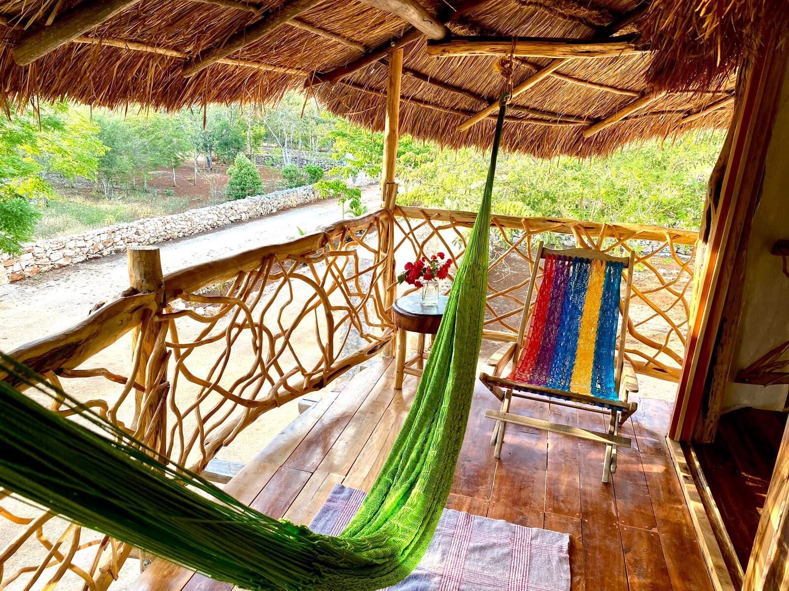 Off-grid ecological cabin porch at Hunab Ku eco aldea — hammocks strung between wooden pillars, surrounded by Yucatán jungle.