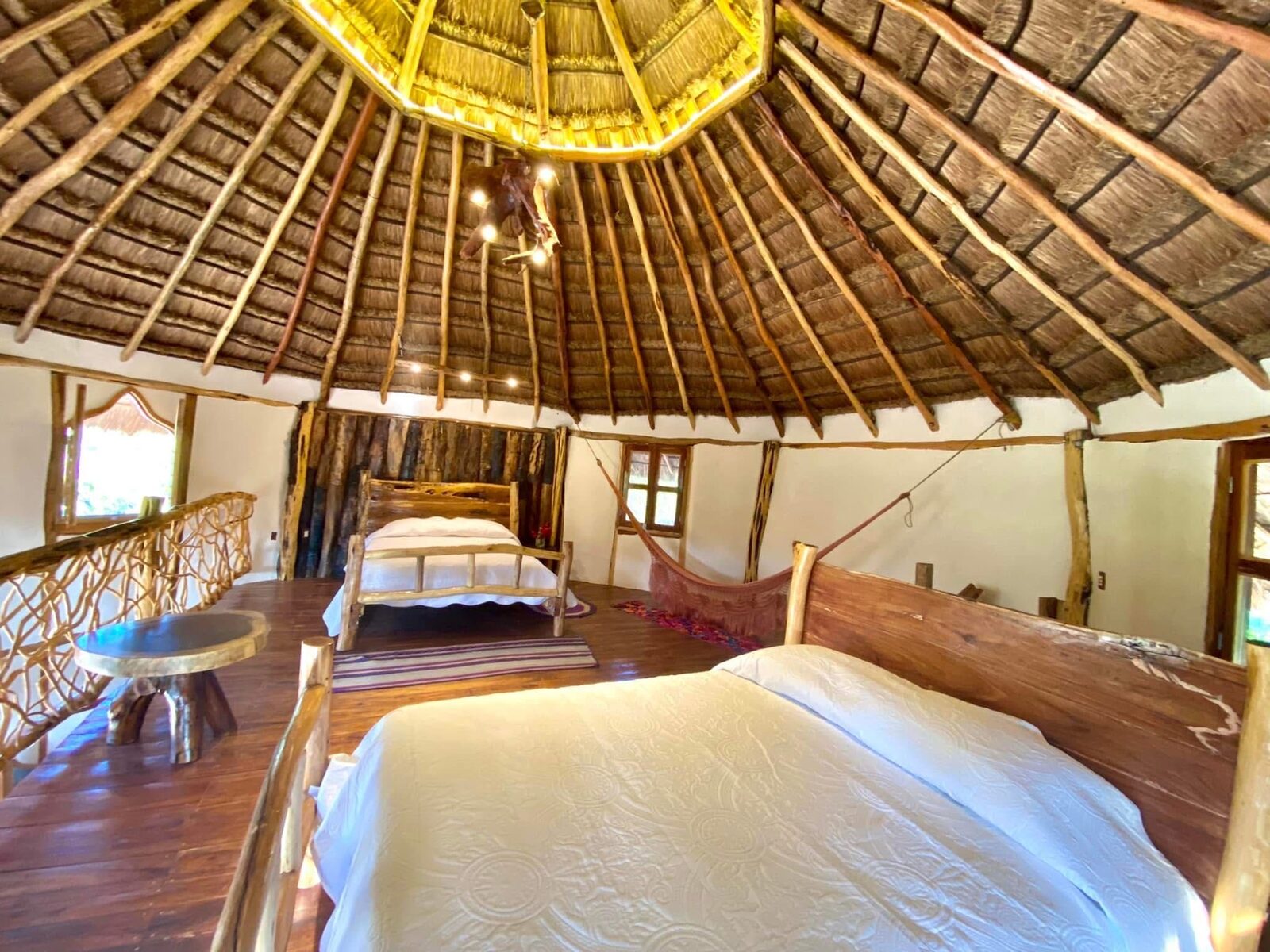 A bedroom beneath a palapa roof, with layered natural textiles.